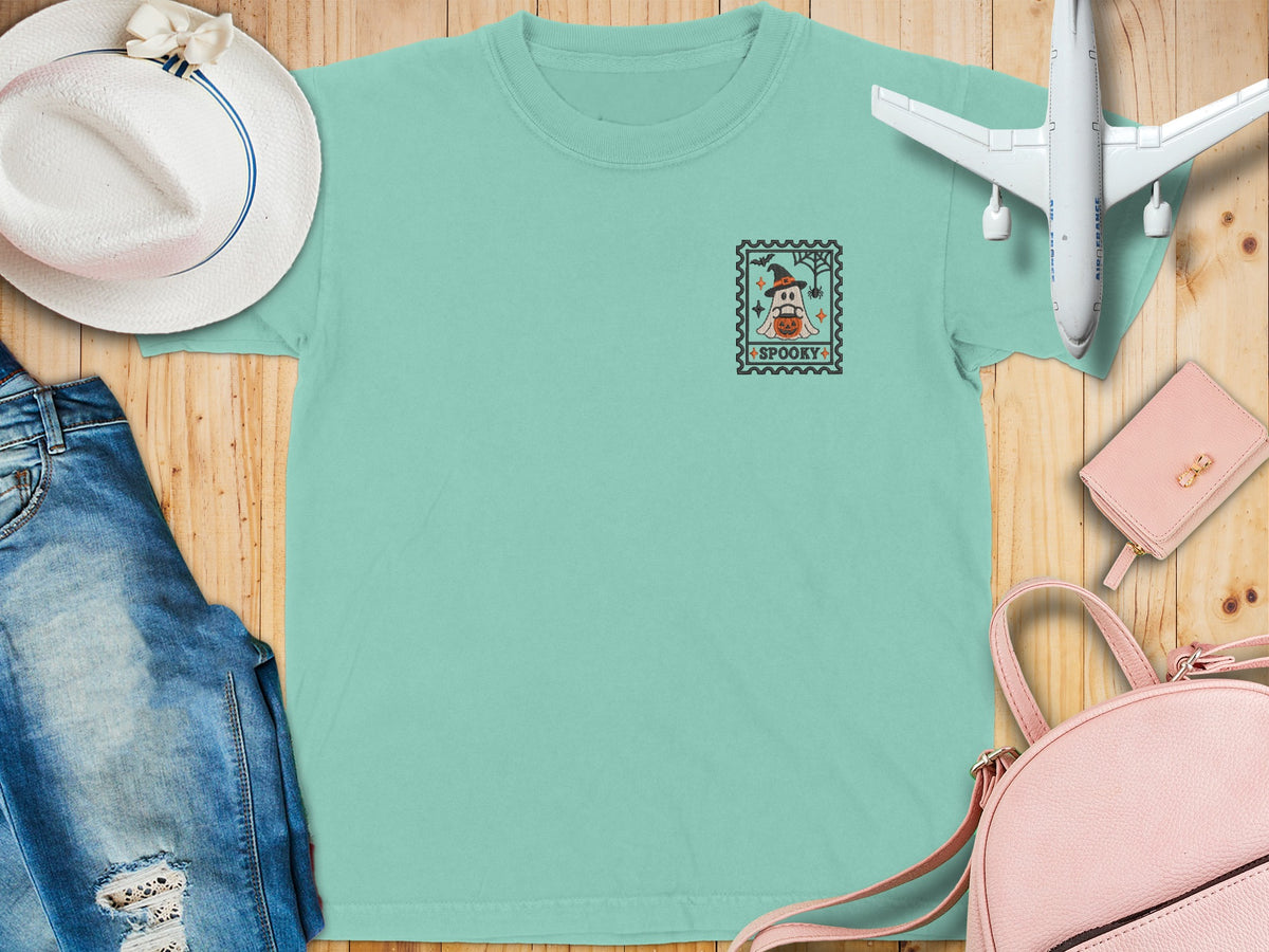 Mint t-shirt with a postage stamp graphic featuring a ghost in a witch hat and pumpkin.